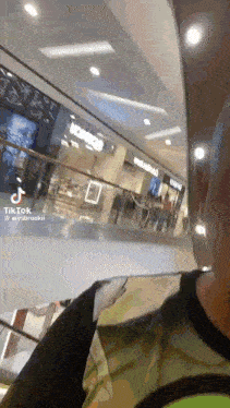 a man is walking down an escalator in a shopping mall
