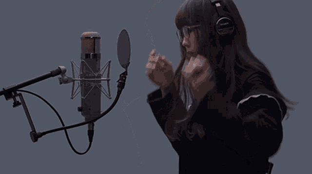 a woman wearing a pair of sony headphones sings into a microphone
