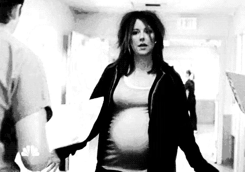 a pregnant woman is walking down a hallway in a hospital while a man holds her hand .