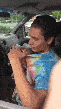 a man in a tie dye shirt sitting in a car