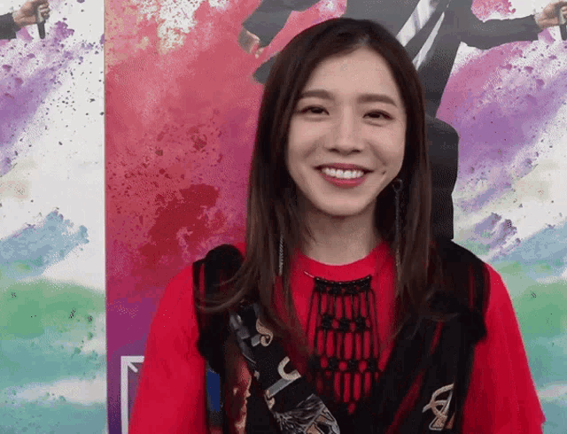 a woman is smiling in front of a colorful background