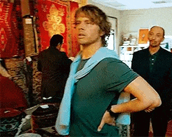 a man is standing with his hands on his hips in a room with other men .