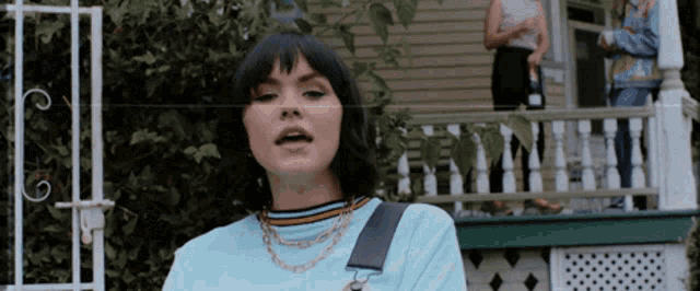 a woman in a blue shirt is standing on a porch with her mouth open
