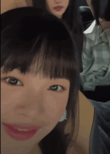 a close up of a woman 's face with a few other people in the background