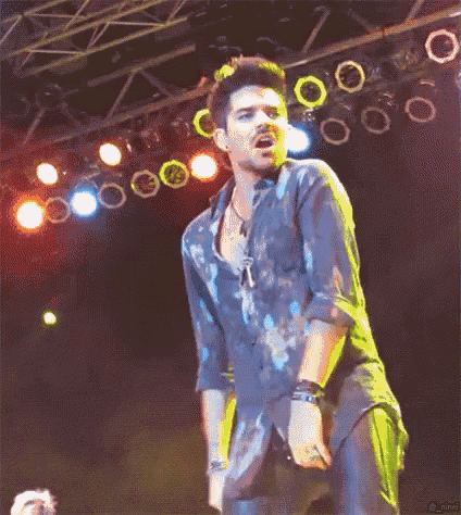 a man in a blue shirt is singing into a microphone