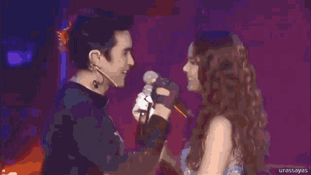 a man and a woman are looking into each other 's eyes while holding microphones in front of them