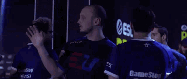 a group of men are standing next to each other in a dark room and giving each other high fives .