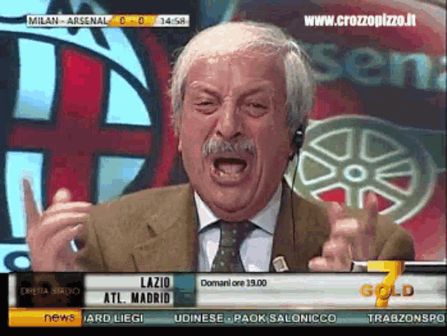 a man in a suit and tie is talking on a television screen that says gold