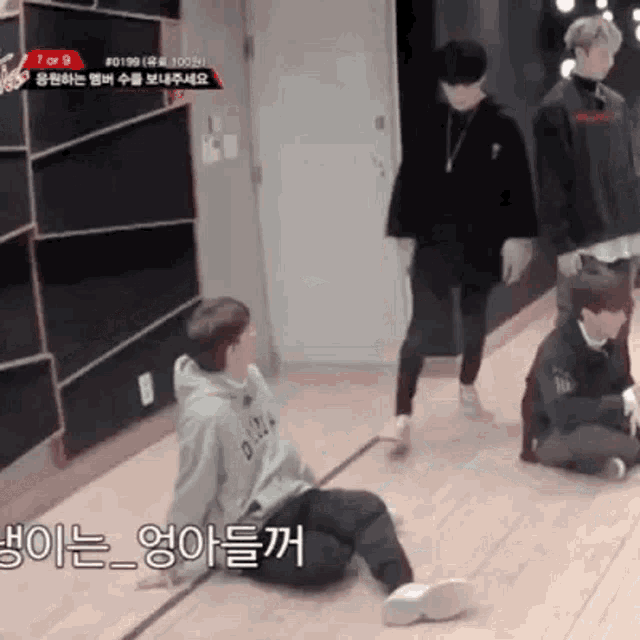 a group of young men are sitting on a wooden floor in a room .