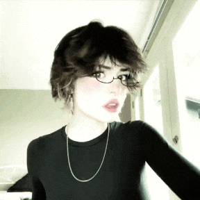 a girl wearing glasses and a necklace is looking at the camera