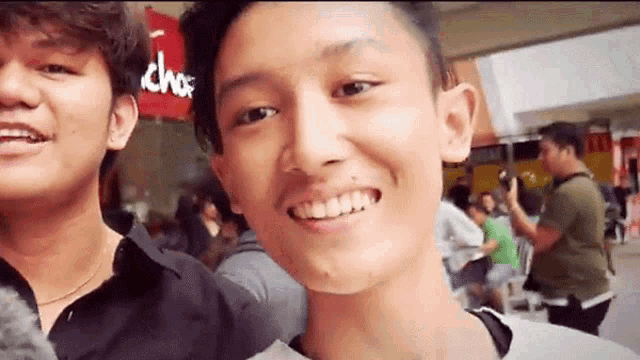 two young men are smiling for the camera in front of a sign that says chop