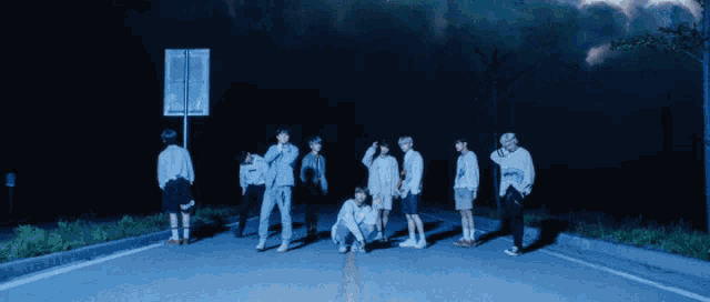 a group of people are standing on a road at night
