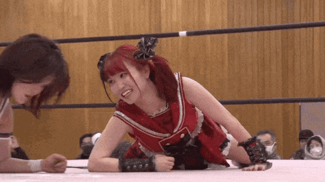 two women are wrestling in a ring and one of them is wearing a red dress