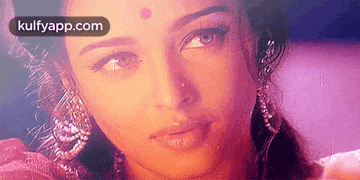 a close up of a woman 's face with a bindi on her forehead and earrings .
