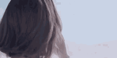 a woman is holding her hair in front of a blue sky in a close up .