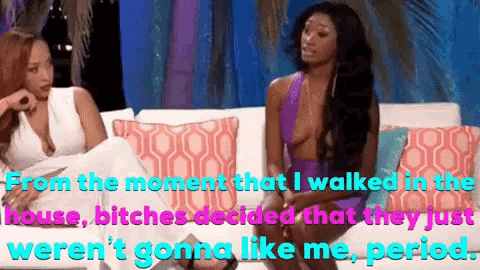 two women are sitting on a couch and one of them is wearing a white dress