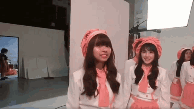 a group of girls wearing pink hats and aprons are standing next to each other and smiling .
