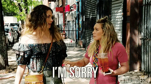 two women are standing on a sidewalk and one of them is saying " i 'm sorry "