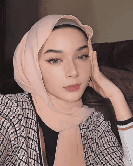 a woman wearing a hijab looks at the camera