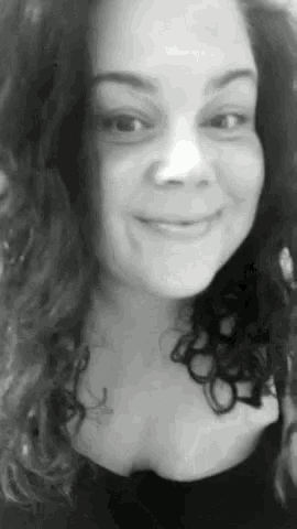a black and white photo of a woman with curly hair smiling for the camera .