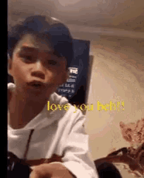 a young boy in a white shirt is making a funny face and says `` love you bah ! ''