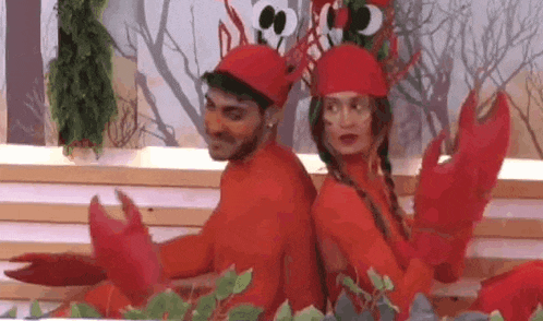 a man and a woman are dressed up as lobsters and dancing back to back .