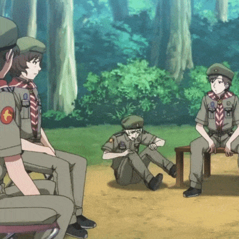 a group of boy scouts are sitting around a table in the woods