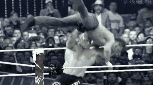a man is being lifted in the air by another man in a wrestling ring in front of a crowd .