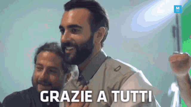 a man says grazie a tutti in front of another man