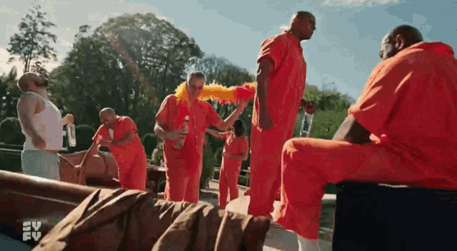 a group of men in orange jumpsuits are standing in front of a tv screen that says ' sv fv ' on it