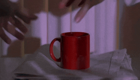 a close up of a person 's hand reaching for a white shirt on a table .