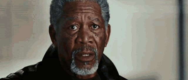 a close up of a man with a beard and gray hair making a funny face .