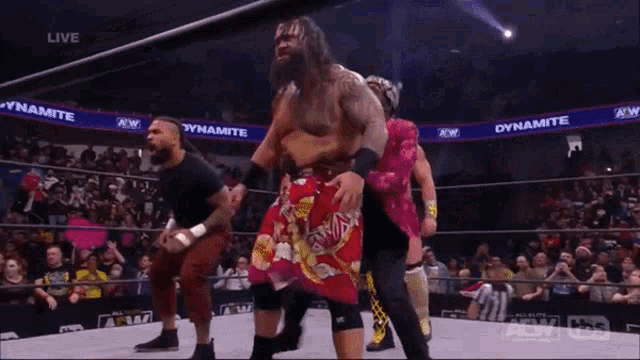 a group of wrestlers in a ring with dynamite written on the walls