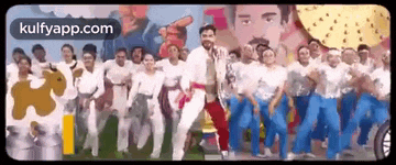 a group of people are standing next to each other and dancing in front of a painting of a man .