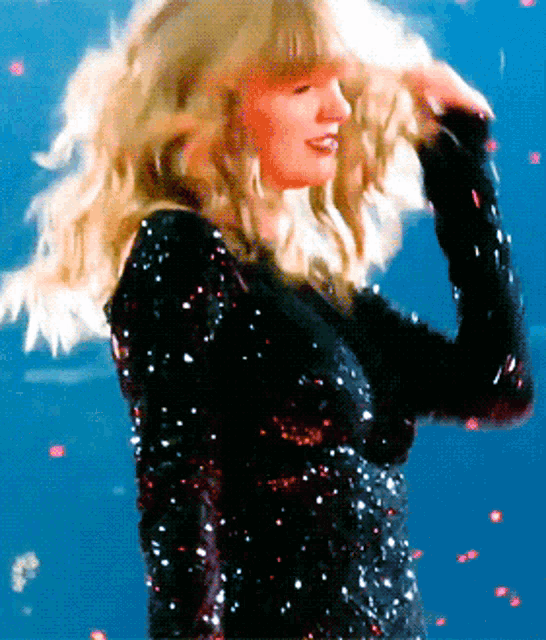 a woman wearing a black sequined top is standing on a stage
