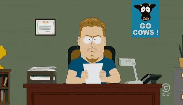 a man sits at a desk with a sign that says go cows