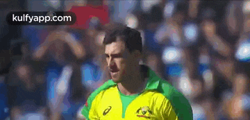 a man wearing a yellow and green jersey is standing in front of a crowd .