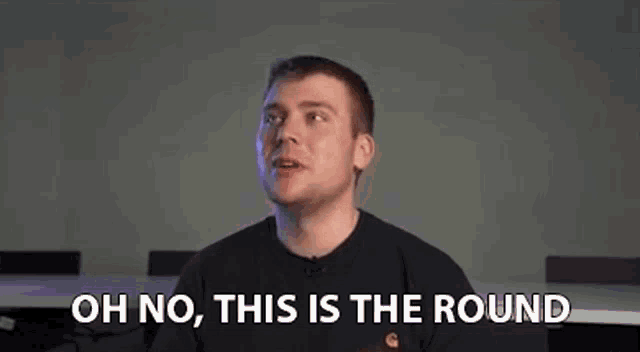 a man is sitting at a table with his mouth open and the words `` oh no , this is the round '' written on the screen .