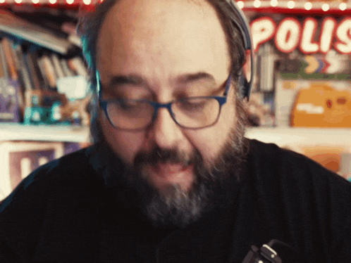 a man with glasses and a beard is wearing headphones in front of a sign that says polis