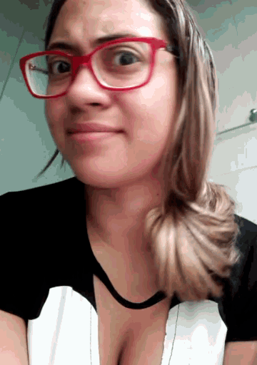 a woman wearing glasses and a black and white shirt makes a funny face