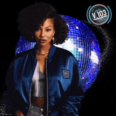 a woman in a blue jacket stands in front of a disco ball with the words v. 103 on the bottom