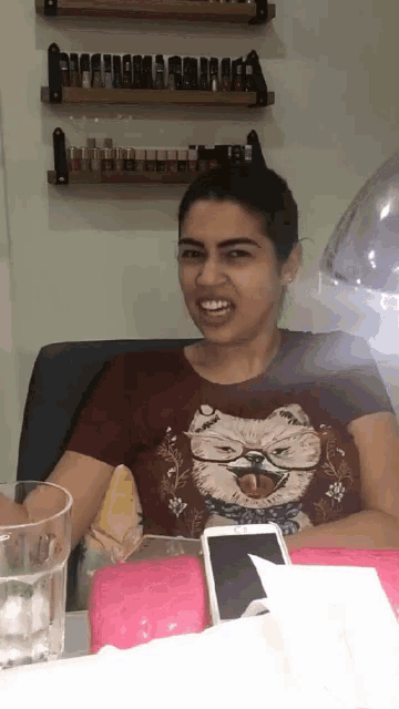 a woman wearing a shirt with a dog on it is sitting at a table