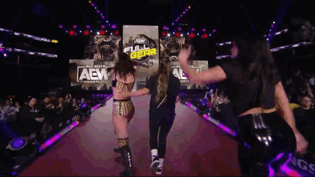 a group of women dancing in front of a aew sign