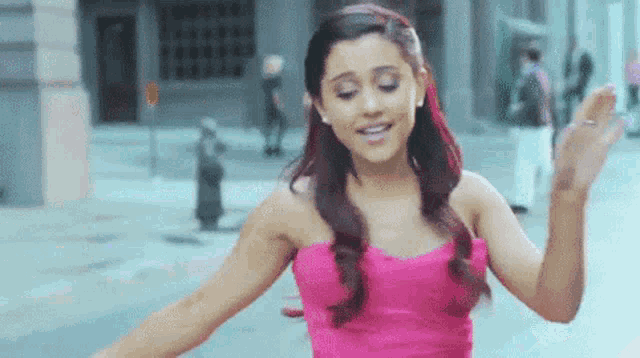 ariana grande is wearing a pink strapless dress and dancing in the street .