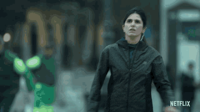a woman in a black jacket is running down a street with a netflix logo in the corner