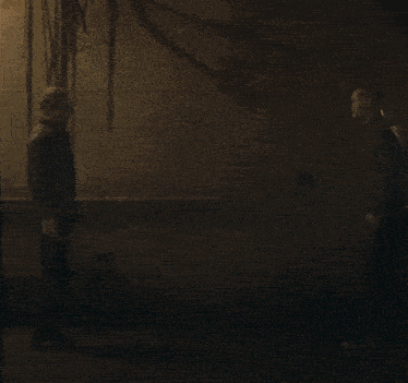 two men are standing next to each other in a dark room and talking
