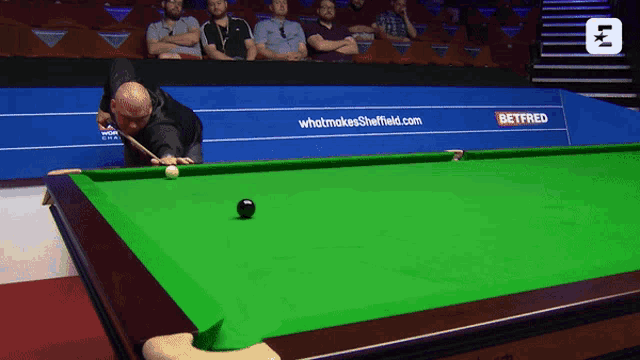 a man is playing snooker in front of a betfred sign