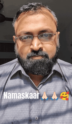 a man with glasses and a beard is wearing a shirt that says namaskaar