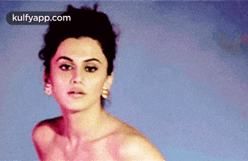 a woman without a shirt is standing in front of a blue wall .