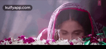 a woman is laying on a bed with her eyes closed and flowers in front of her .